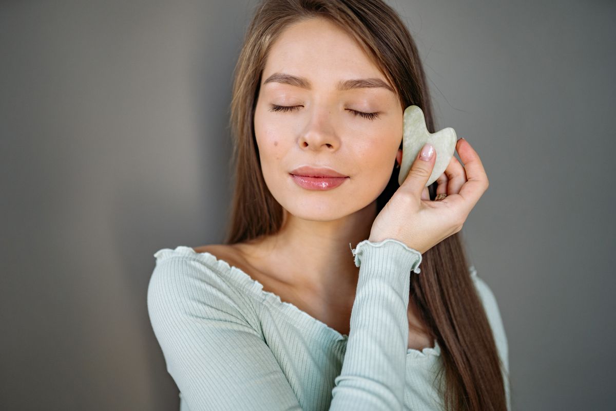 Femme utilisant un gua sha sur le visage