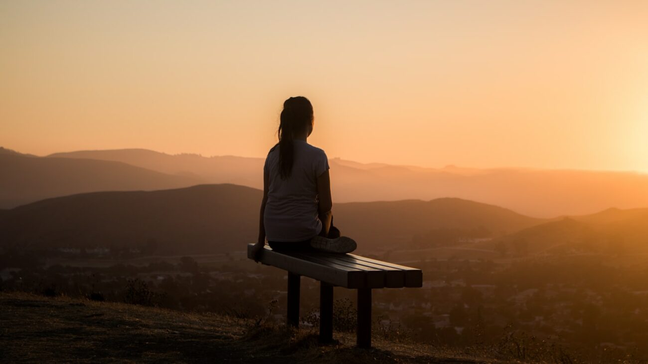 Femme détendue assise face à un paysage de montagne, visualisation positive